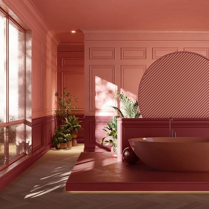 Salle de bain contemporaine aux murs habillés de moulures Orac Decor dans des tons de rose et de bordeaux. L’espace met en valeur une baignoire ovale assortie et un grand panneau décoratif rond, soulignant la richesse des textures et la capacité des profilés Orac à structurer les volumes avec élégance.